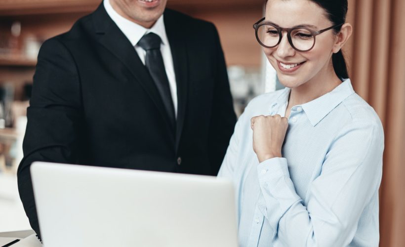 two-smiling-businesspeople-using-a-laptop-together-in-an-office.jpg